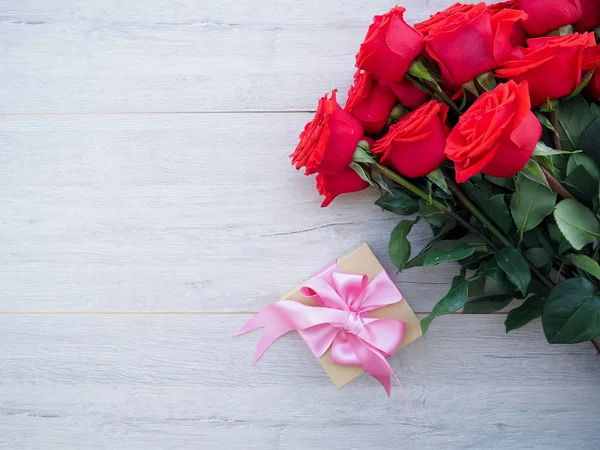 Kurdele ve yay ve ahşap kırmızı güller demet ile hediye kutusu Valentine arka plan. Kopyalama alanı