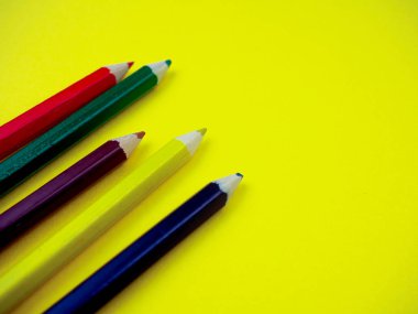 sarı bir arka planda renkli kalemler, metin için alan.