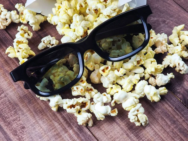 3D glasses on the background of the row of popcorn for movies, space, on wooden background
