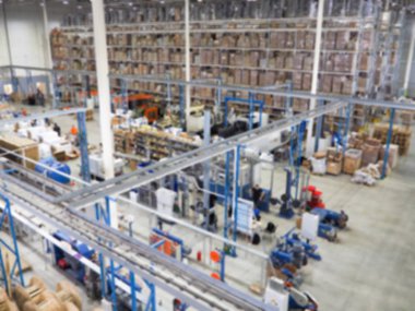Ambar iç, ambar Sanayi ve lojistik hizmet veren firma kayıtları Ticari ambar. Kutuları ve üç katlı raflarında stok kasaları. Hareket etkisi bulanıklık. Parlak güneş ışığı.
