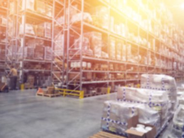 Ambar iç, ambar Sanayi ve lojistik hizmet veren firma kayıtları Ticari ambar. Kutuları ve üç katlı raflarında stok kasaları. Hareket etkisi bulanıklık. Parlak güneş ışığı.