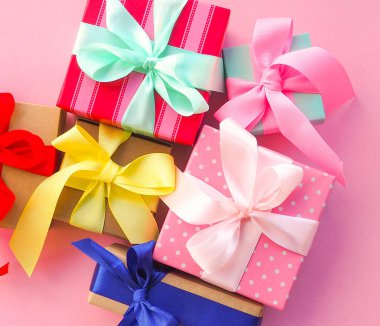 Pembe arka planda kurdele ile pembe Noel hediyesi.