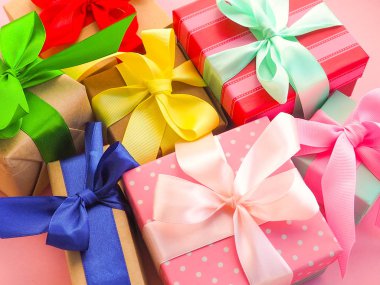 Pembe arka planda kurdele ile pembe Noel hediyesi.