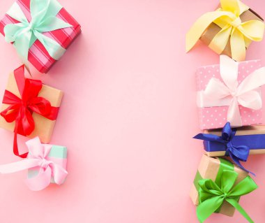 Pembe arka planda kurdele ile pembe Noel hediyesi.