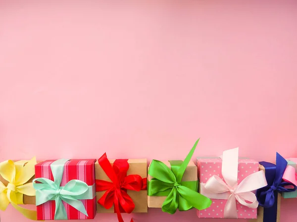 Pink Christmas gift with ribbon, on pink background.