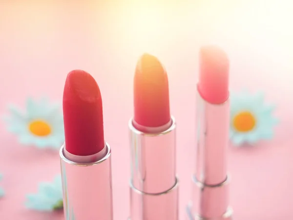 three tubes of lipstick on pink background, the concept of beauty.