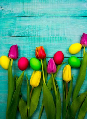 Ahşap arka planda Paskalya yumurtaları ve taze bahar lale.