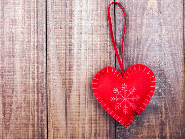 red and white heart with snowflake on wooden background, copy space.