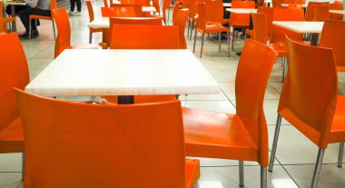 Salonda bulanık insanlar arka plan ile satırda düzenlenmiş boş sarı renk sandalyeler. turuncu sandalyeli yemek odası, bulanık.