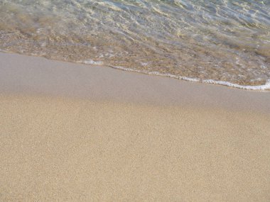 Kumlu sahilde yumuşak bir mavi okyanus dalgası. Arkaplan