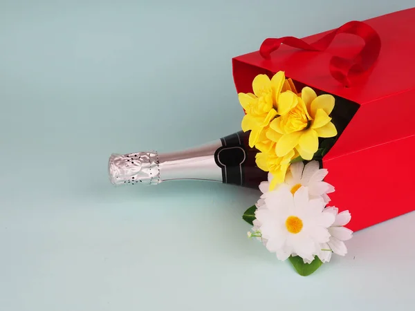 bottle of wine and flowers in the package on blue background, space for text.