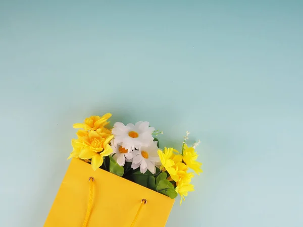 bottle of wine and flowers in the package on blue background, space for text.