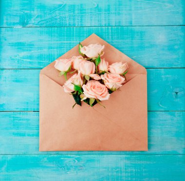 Aşk ya da Sevgililer günü konsepti. Ahşap bir arka planda zarf kırmızı güzel güller. Üst görünüm