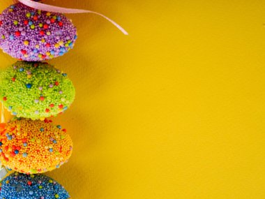 Paskalya tatili geçmişi. Parlak sarı arka planda renkli paskalya yumurtaları..