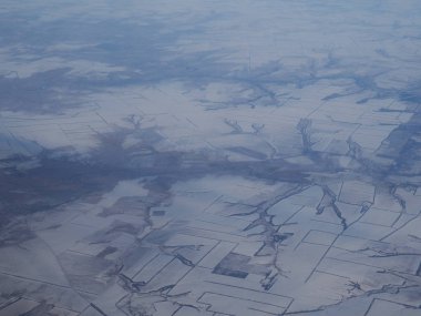 Bulutlarla kaplı karlı dağların havadan görünümü. Dağ üstü uçaktan kış görünümünde bulutlar ile kaplı.