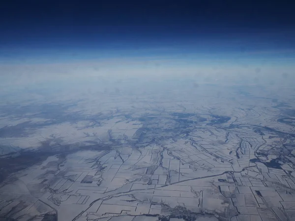 Vue aérienne des montagnes enneigées couvertes de nuages. Montagne couverte de nuages en vue d'hiver depuis l'avion . — Photo