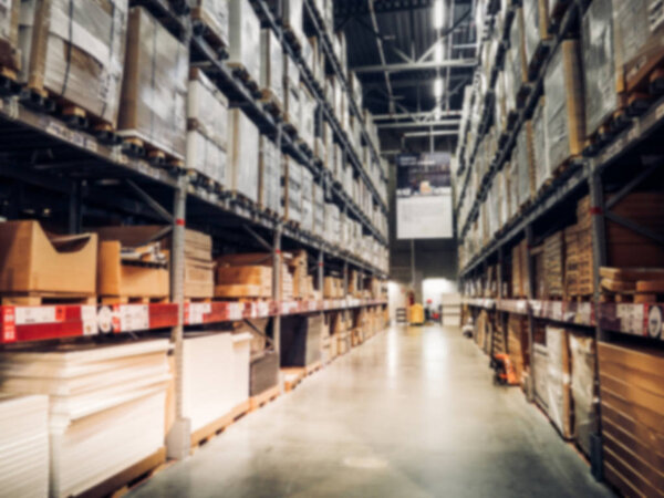 Blurred boxes on rows of shelves in warm light warehouse backgro