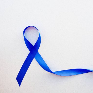 Beyaz arka planda iz bırakan mavi farkındalık kurdelesi, kalın bağırsak için koyu mavi kurdele - kolorektal kanser ve Akut Solunum Sıkıntısı Sendromu destekçilerinin elinde farkındalık yaratıyor