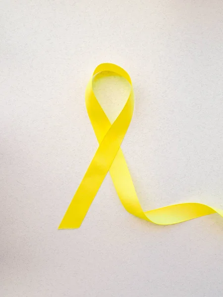 Yellow awareness ribbon on light background, Yellow ribbon symbolic color for Sarcoma Bone cancer, Spina Bifida Awareness Month and suicide prevention on helping hand