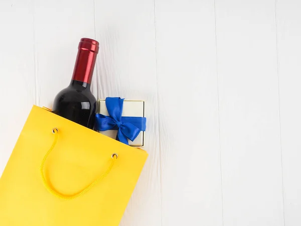 bottle of wine in the package with a gift, flowers, on wooden ba