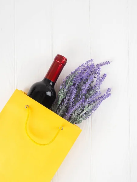 Botella de vino en el paquete con un regalo, flores, en ba de madera — Foto de Stock