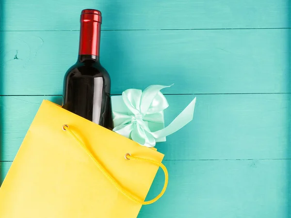 bottle of wine in the package with a gift, flowers, on wooden ba