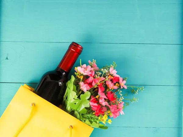 Бутылка вина в пакете с подарком, цветы, на деревянной ба — стоковое фото