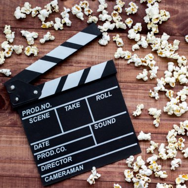 Filmi izliyorum. Film clapperboard ve patlamış mısır mavi ahşap masa arka plan üst görünüm copyspace