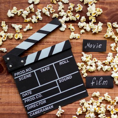 Filmi izliyorum. Film clapperboard ve patlamış mısır mavi ahşap masa arka plan üst görünüm copyspace