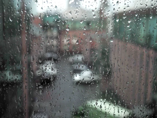 Krople deszczu na brudne szklane tło, samochody miejskie przez deszcz na oknie — Zdjęcie stockowe