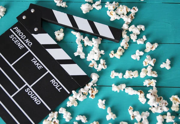 Popcorn på en blå trä bakgrund, ovanifrån, bredvid en flik täljare för filmer — Stockfoto