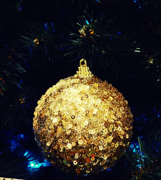 Primer plano de Bauble colgando del árbol de Navidad iluminado. Bolas y baratijas navideñas como fondo para postales, muchos juguetes navideños diferentes en luces sin foco, primer plano — Foto de Stock