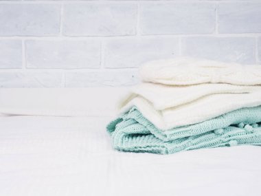 Beyaz bir yatakta sıcak örülmüş şeyler yığını. Samimi kıyafetler. Ev kavramı. Katlanmış şeyler beyaz..