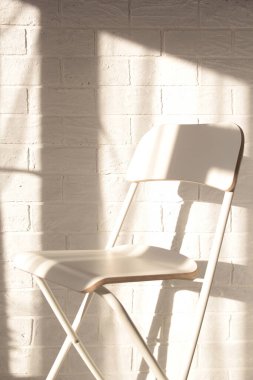 Hafif minimalizm modern İskandinav tavan arası stüdyo dairesi. Pencerenin yanındaki beyaz duvara dayalı kafe mobilya koltuğu. Gölgeler öğleden sonra kalıp kopyalama arkaplanı