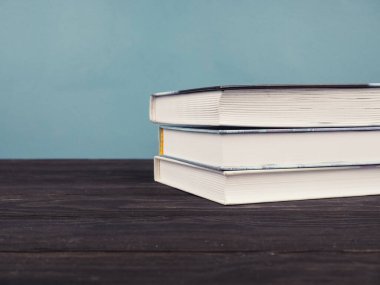 Mavi arka planda fotokopi alanı olan bir kitap yığını. Eğitim ve eğitim kavramı.