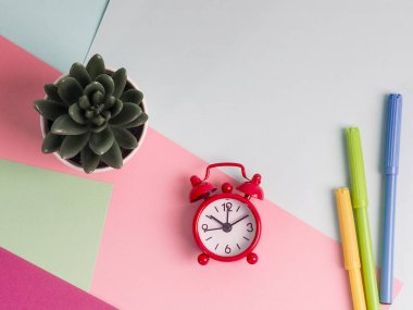 Çok Renkli Arkaplanda Alarm Saati, Not Defteri, Kalem ve Saksı Bitkisi.