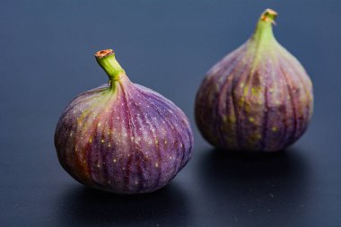Yumuşak tonlu nötr bir arka planda tek bir olgun incir izole. Yazı işleri, ambalaj ya da aşçılık için temiz ve zarif bir yemek fotoğrafı.