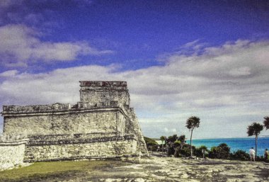 Meksika, Yucatan, Tulum. 28 Aralık 2000. Yucatan Meksika kıyılarında bulunan antik Maya bölgesi Tulum. Görüntüde, turkuaz sulara bakan ve tropikal bitki örtüsüyle çevrili tarihi taş yapılar yer alıyor.