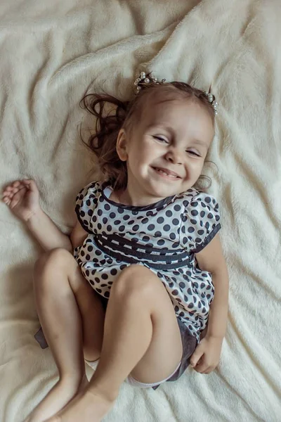 Kleines Mädchen Lächelnd Auf Dem Bett Liegend Stockbild