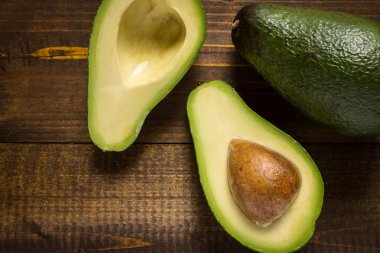 Koyu ahşap arka plan üzerinde avokado. Sağlıklı gıda kavramı.