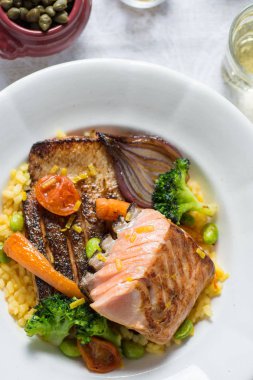 Beyaz tabakta sebzeli ızgara somon fileto