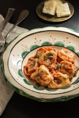 Taze ev yapımı Tortellini domates sosu ve rustik plaka üzerinde Mozzarella peyniri ile