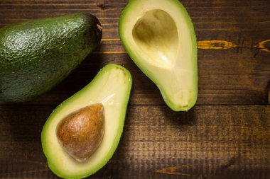 Koyu ahşap zemin üzerine taze avokado. Sağlıklı gıda kavramı.