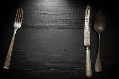 Eski rustik çatal bıçak takımı koyu ahşap zemin üzerinde. Mutfak ve gıda kavramı.