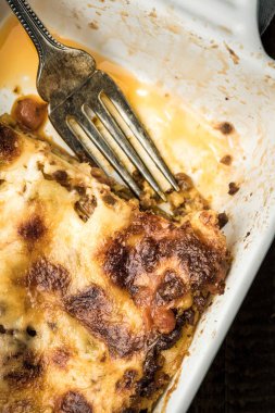 Koyu ahşap arka plan üzerinde çatal ile İtalyan lazanya yemek