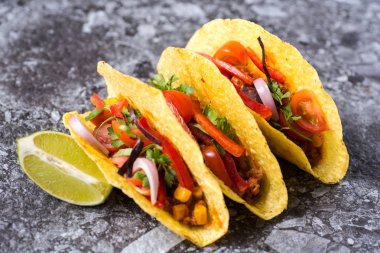 Üç renkli Meksika Tacos taş zemin üzerine kabuklarında