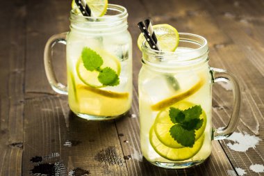 Soğuk taze limonata Mojito kokteyl buz, limon ve nane ile Mason kavanoza rustik koyu ahşap arka plan üzerinde bırakır. Yaz konsepti.