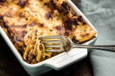 Koyu ahşap arka plan üzerinde çatal ile İtalyan lazanya yemek