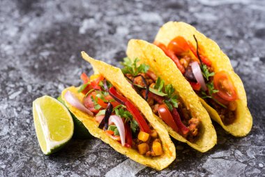 Üç renkli Meksika Tacos taş zemin üzerine kabuklarında