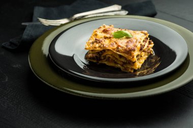 Geleneksel lazanya kıyma, Bolognese sos ve fesleğen karanlık plaka üzerinde. İtalyan mutfağı.